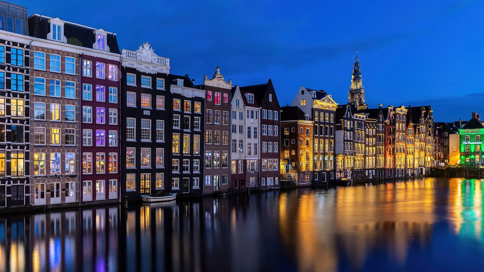 Is Amsterdam veilig? Grachtenpanden aan het Damrak in Amsterdam in het blauwe uur