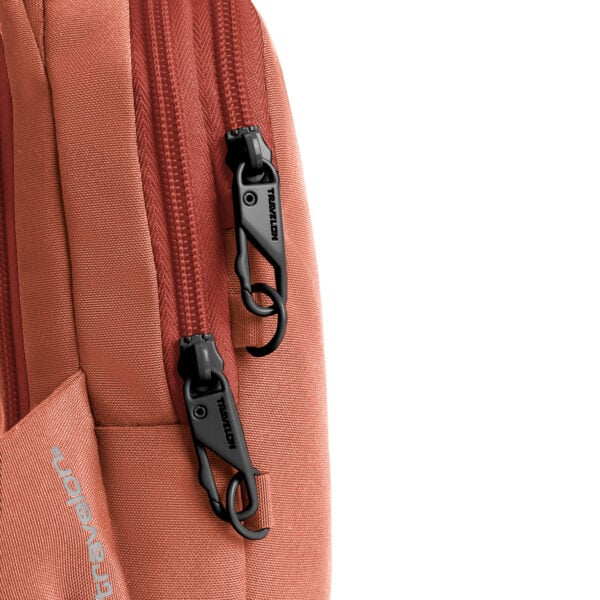 Detail van de twee vergrendelbare ritsen op de Travelon Voyages compact sling in koraal