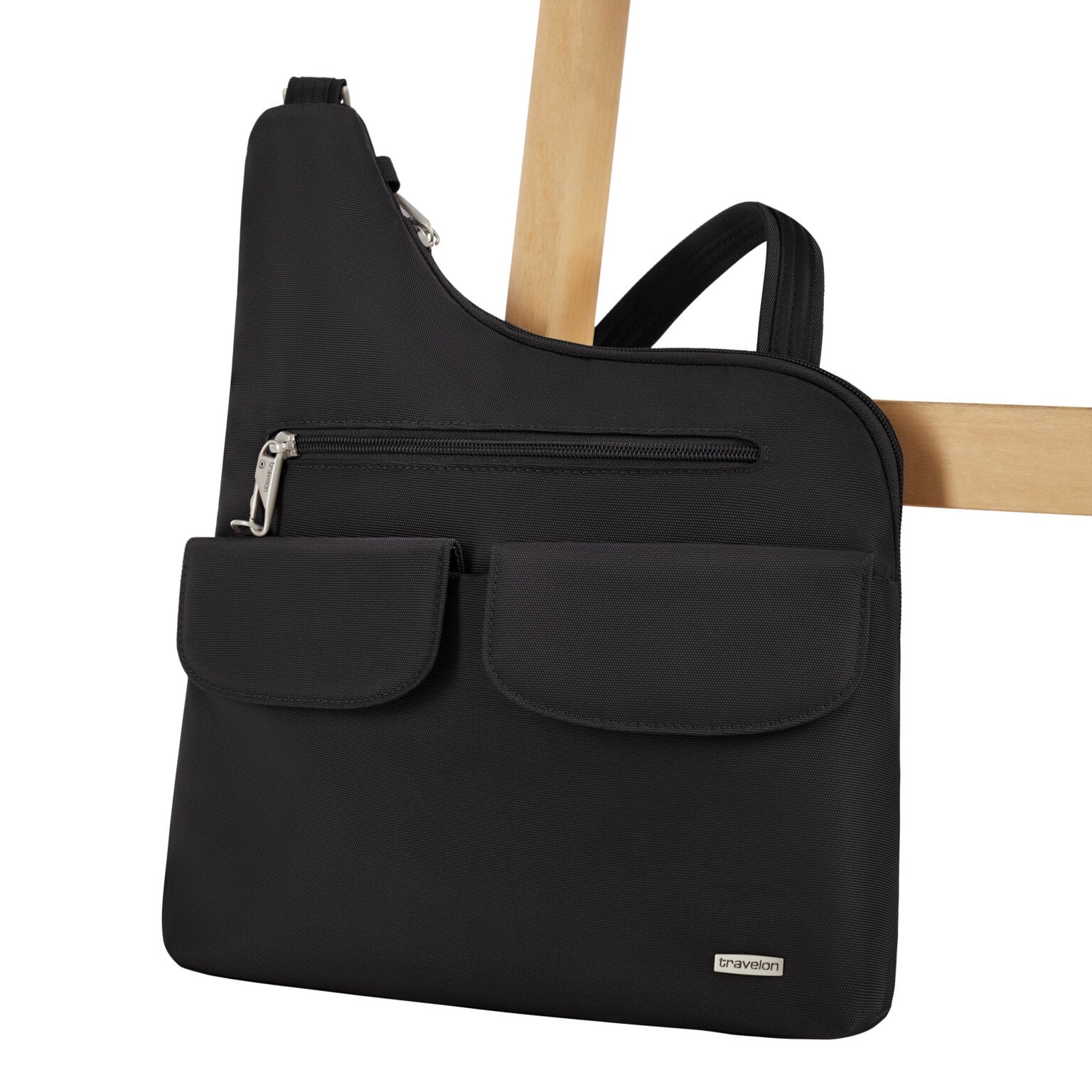 De Travelon Classic grote crossbody tas in zwart vastgezet aan de poot van een stoel