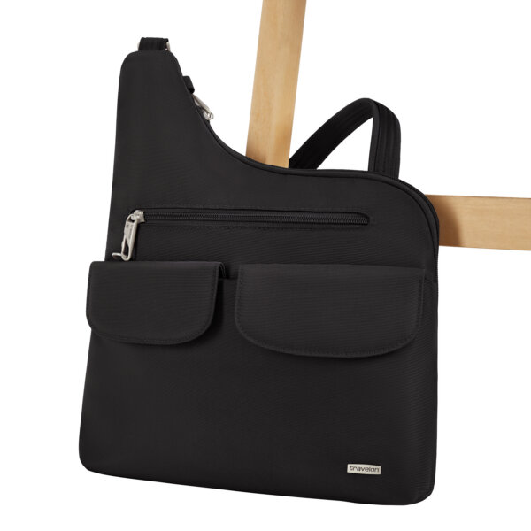 De Travelon Classic grote crossbody tas in zwart vastgezet aan de poot van een stoel