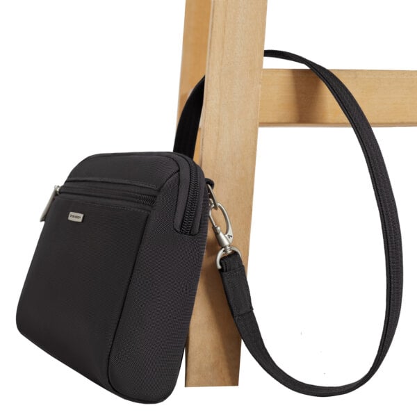 De Travelon Classic kleine crossbody of heuptas in zwart vastgezet aan de poot van een stoel