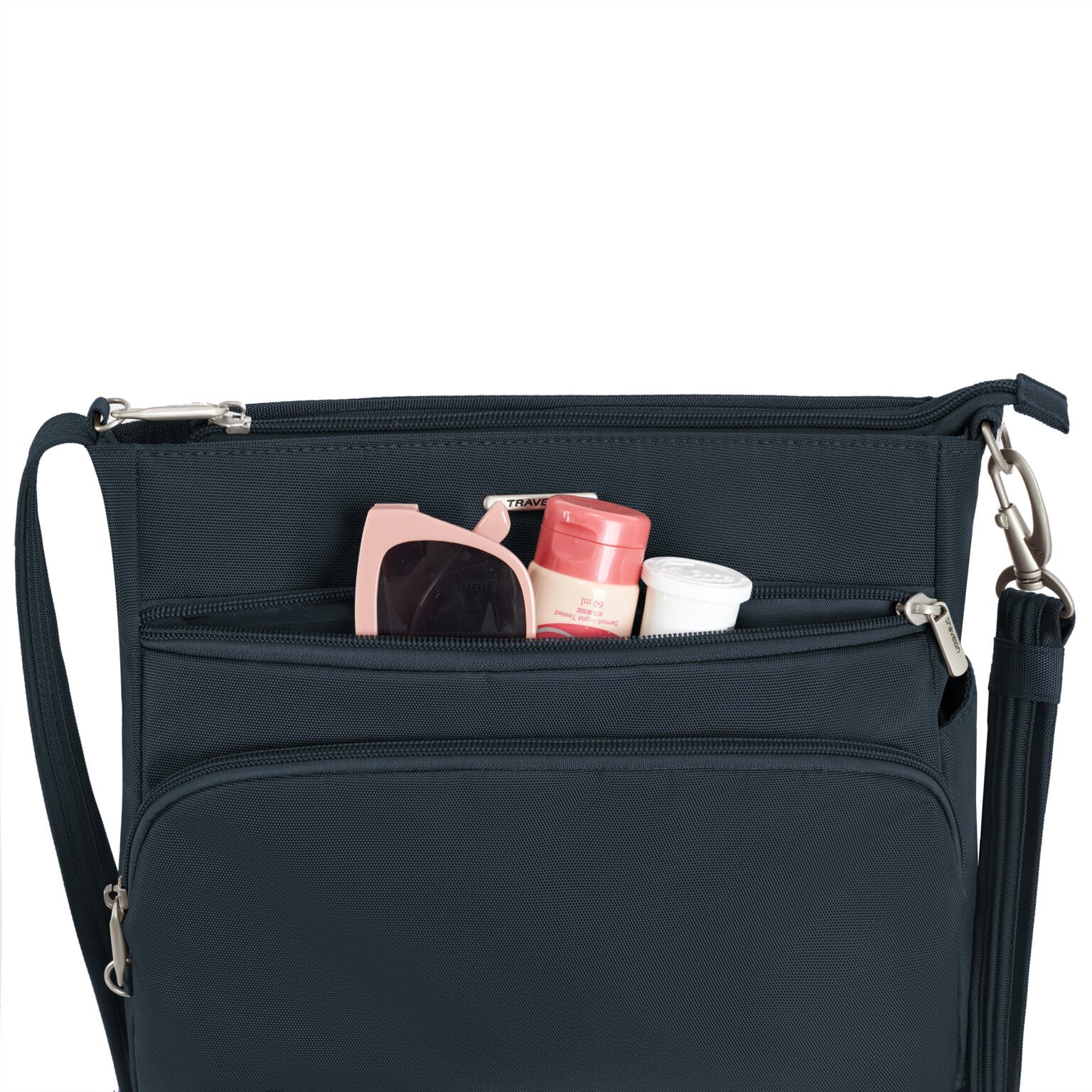 Voorvak van de Travelon Classic N/S crossbody tas in midnight blauw met zonnebril en verzorgingsspullen