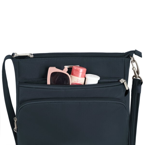 Voorvak van de Travelon Classic N/S crossbody tas in midnight blauw met zonnebril en verzorgingsspullen