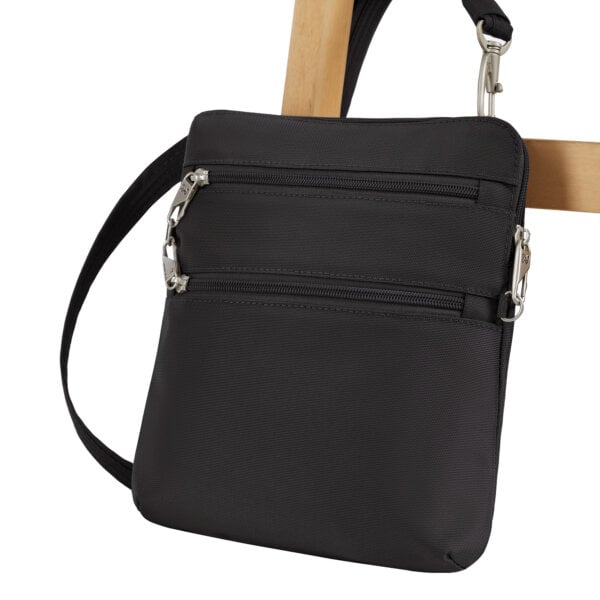 De Travelon Classic slanke crossbody tas in zwart vastgezet aan de poot van een stoel