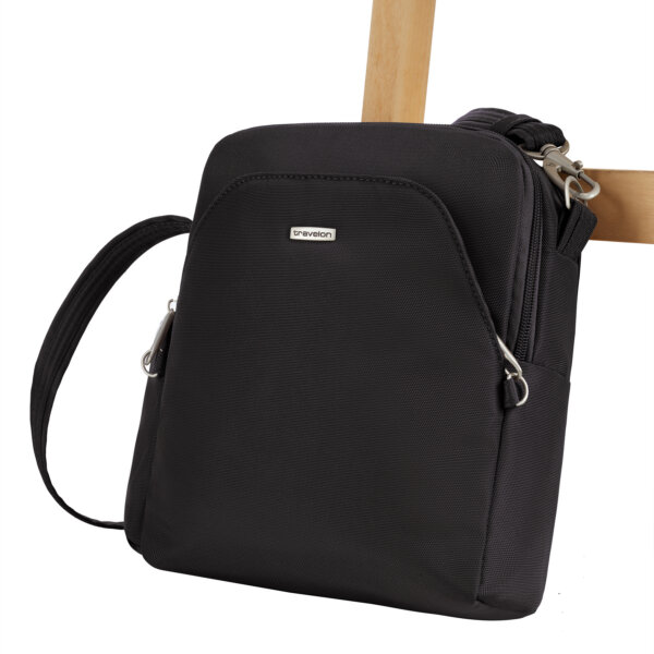 De Travelon Classic travel bag in zwart vastgezet aan de poot van een stoel