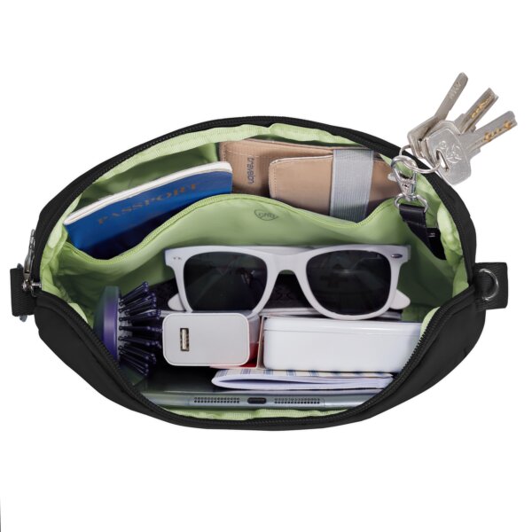 Gevuld hoofdvak van de Travelon Roam brede crossbody tas in zwart met zonnebril, powerbank en sleutels